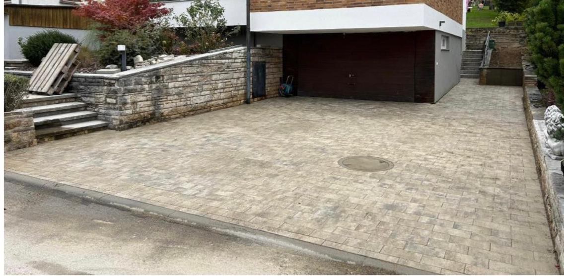 Einfahrt nach der Pflasterung mit Natursteinmauer und Garagenvorplatz