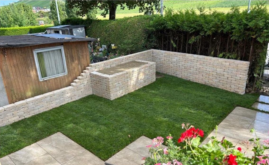 Garten nach dem Umbau: Natursteinmauer, frischer Rollrasen und Terrassenplatten