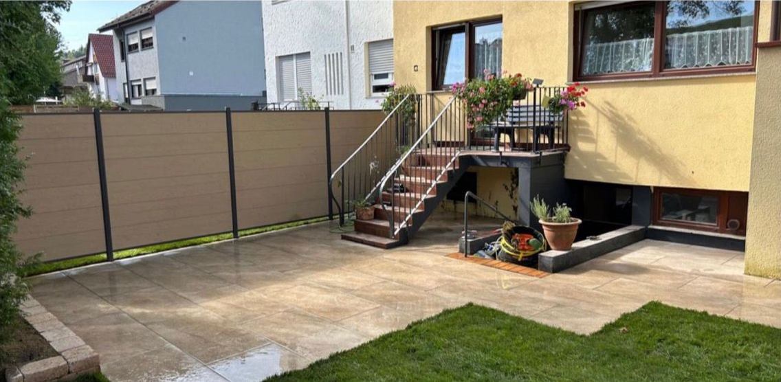Hintergarten nach dem Umbau: Terrassenplatten, Sichtschutzzaun und Rasen