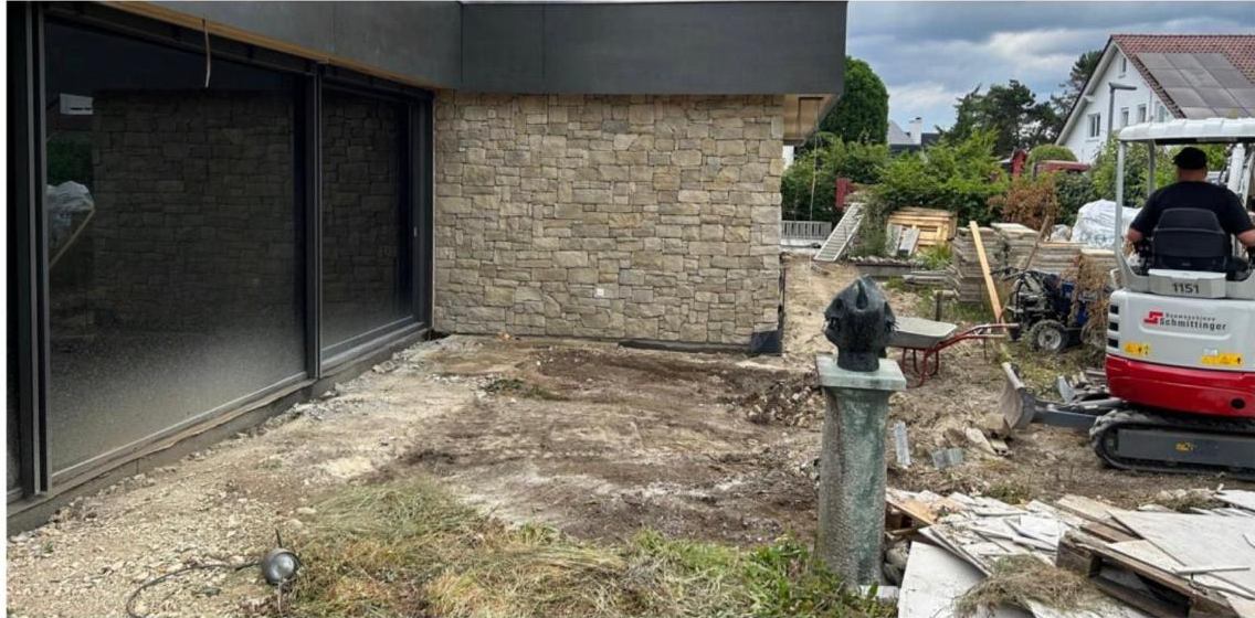 Dieselbe Fläche vor dem Umbau: Erdreich, Baumaterial und ein Minibagger