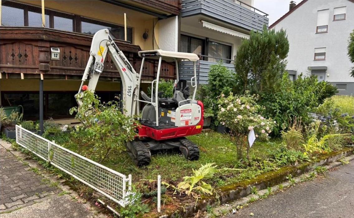 Vorgarten vor dem Umbau: Minibagger zwischen Beeten und Sträuchern
